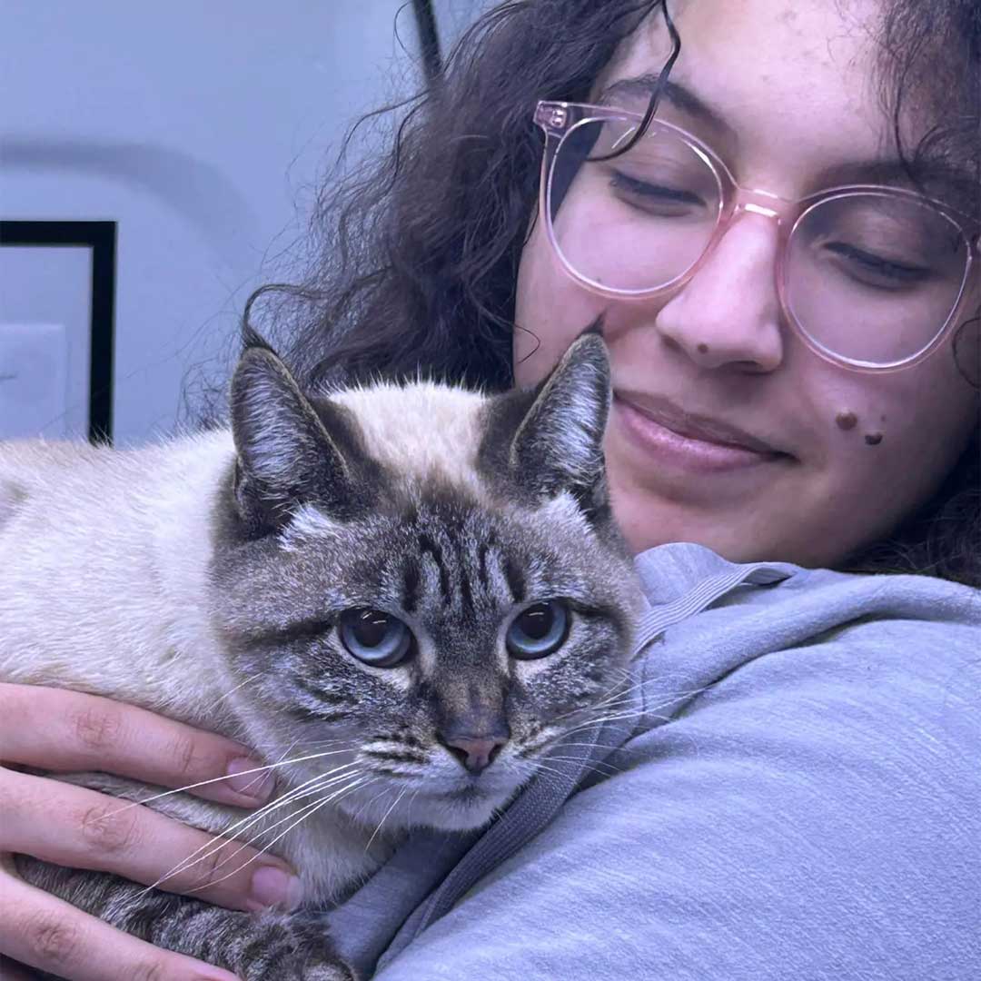 Our member with glasses gently holds a cat, smiling warmly at the camera.